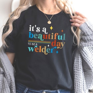 May include: Black t-shirt with the text "it's a beautiful day to be a welder" in colorful letters.