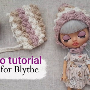 Puede incluir: Un gorro de crochet en rosa, blanco y marrón con un borde rizado. El gorro está en una muñeca con cabello largo gris. El texto "Crochet" está en la esquina superior derecha de la imagen. El texto "Video tutorial Sombrero para Blythe" está en la esquina inferior izquierda de la imagen.