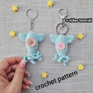 May include: Two crocheted blue octopus keychains with pink buttons. The keychains are hanging from silver key rings. The text "crochet pattern" is written on the surface below the keychains.