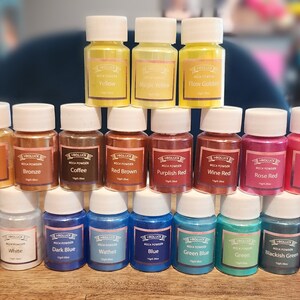 May include: A collection of 24 small glass bottles filled with mica powder in various colors, including orange, golden, bronze, coffee, red brown, purplish red, wine red, rose red, pink, watermelon, silver gray, black, white, dark blue,  wathet, blue, green blue, green, blackish green, purple, and peach. The bottles are labeled with the color name and "Mica Powder".