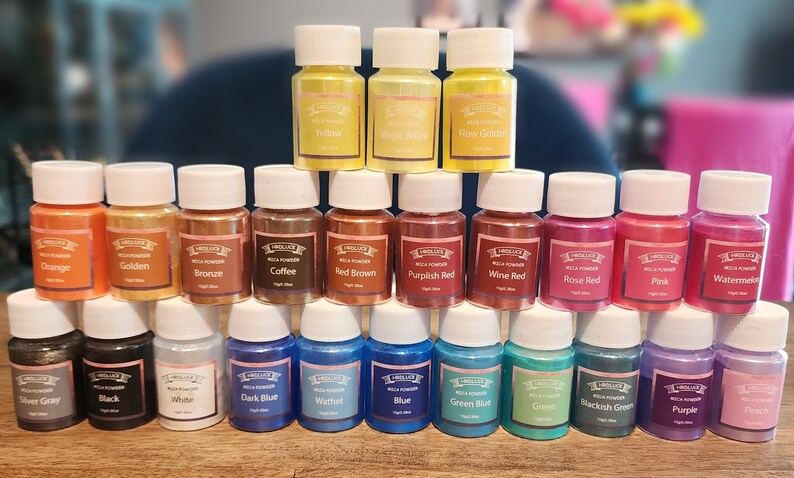 May include: A collection of 24 small glass bottles filled with mica powder in various colors, including orange, golden, bronze, coffee, red brown, purplish red, wine red, rose red, pink, watermelon, silver gray, black, white, dark blue,  wathet, blue, green blue, green, blackish green, purple, and peach. The bottles are labeled with the color name and "Mica Powder".