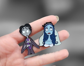 May include: Two enamel pins featuring characters from the movie 'The Corpse Bride'. The pin on the left is a gray-toned man with a purple tie, and the pin on the right is a blue-toned woman with a white veil.