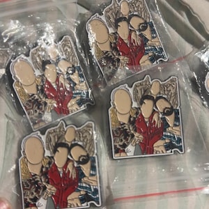 Pode incluir: Quatro pinos de esmalte representando um grupo de quatro pessoas com roupas coloridas. Os pinos estão embalados individualmente em sacos de plástico.