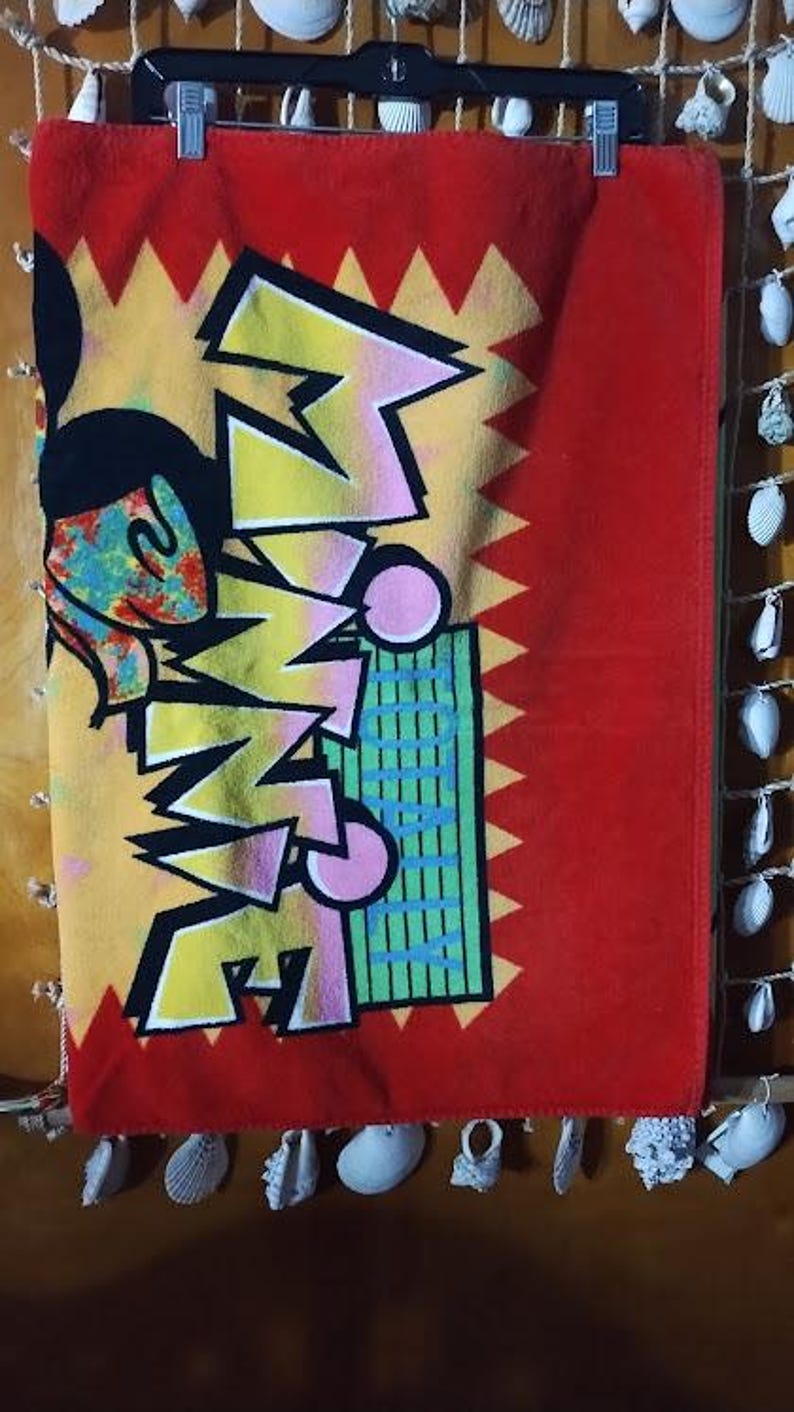 May include: A red beach towel with a yellow, pink, and blue graphic of Mickey Mouse and the word "SUMMER" in a stylized font.