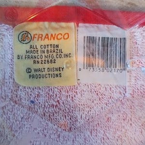 May include: A white towel with a red border and a yellow label that reads "FRANCO ALL COTTON MADE IN BRAZIL BY FRANCO MFG. CO. INC. RN22682 &copy; WALT DISNEY PRODUCTIONS" and a barcode with the number "0 73558 02170".