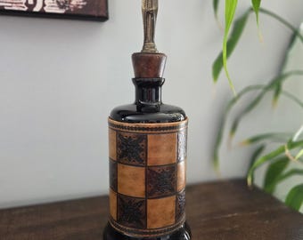 Decantador italiano antiguo de cristal negro con tapón de metal forrado en cuero.