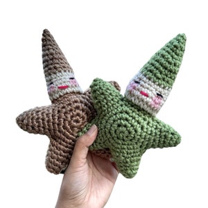 May include: Two crocheted gnome ornaments in the shape of stars. One is brown and the other is green.