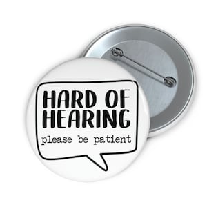 May include: White button with black text that reads "HARD OF HEARING please be patient" in a speech bubble.