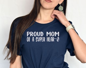 Può includere: Una maglietta blu navy con il testo "Proud Mom of a Super Hear-o" in lettere bianche.