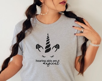 May include: A gray t-shirt with a black unicorn graphic and the text "hearing aids are magical".