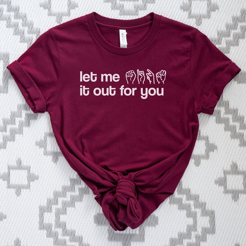 May include: A maroon t-shirt with the text "let me it out for you" in white lettering. The text includes a sign language interpretation of the phrase.