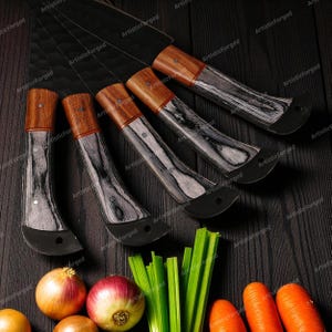 May include: A set of five kitchen knives with black blades and wooden handles. The handles have a two-tone design with a light wood top and a black and gray patterned base. The knives are arranged on a dark wooden surface with vegetables.