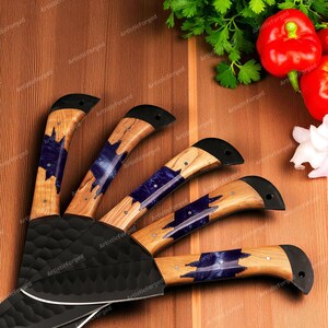 May include: Set of kitchen knives with wooden handles featuring blue and black accents. The blades are black and have a textured surface. The handles have a unique design with a black end.