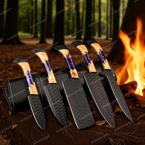 May include: A set of six handcrafted kitchen knives with black blades and wooden handles. The handles feature a light wood grain with blue and purple accents. The knives are displayed on a dark surface with a forest background and a campfire.