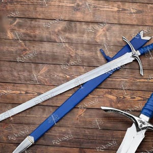 May include: Two silver swords with blue scabbards and handles. The swords have a pointed tip and a curved guard. The swords are lying on a wooden surface.