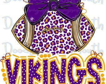 May include: A purple and gold football with a leopard print design and a large purple bow. The word "VIKINGS" is written in purple with white polka dots and outlined in gold.