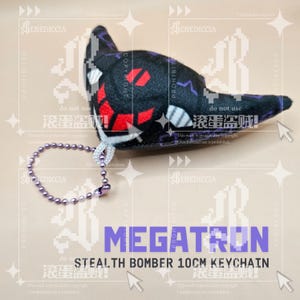 May include: A plush keychain shaped like a stealth bomber, featuring a black exterior with red and white geometric accents. The item includes a purple ball chain attachment and is labeled with the text MEGATRON STEALTH BOMBER 10CM KEYCHAIN.