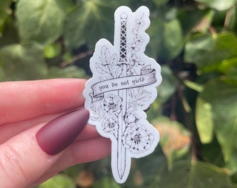 May include: A white sticker with a black line drawing of a sword with flowers and a banner that reads "you do not yield".