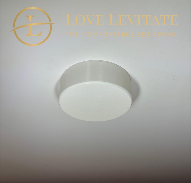 May include: White round ceiling mount for a swing. The mount is made of plastic and has a smooth surface.