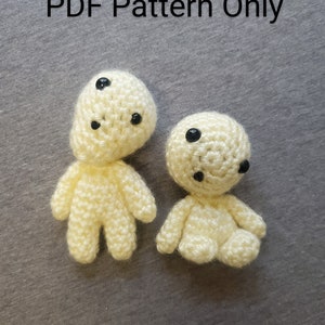 May include: Two small, cream-colored crochet figures with black eyes and small limbs. One figure is standing, the other is sitting. The text "PDF Pattern Only" is above the figures.