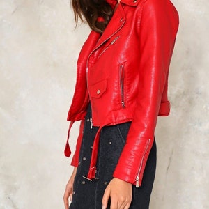 May include: A red faux leather moto jacket with a zipper closure and a belt at the waist.