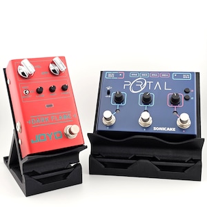 May include: A red Joyo Dark Flame guitar effects pedal and a blue Sonicake Portal guitar effects pedal, both resting on black plastic stands. The red pedal features silver knobs and teal text, while the blue pedal has black knobs and white text.