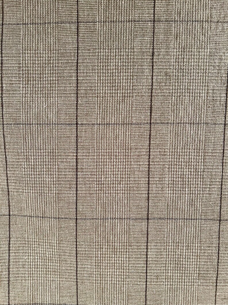 K&ouml;nnte beinhalten: Nahaufnahme eines strukturierten Stoffes mit einem Karomuster. Der Stoff ist haupts&auml;chlich hellbraun oder beige, mit einem Gitter aus d&uuml;nnen, dunkelbraunen Linien, die das Karomuster bilden. Das Gewebe scheint eng und der Stoff hat einen subtilen Glanz.