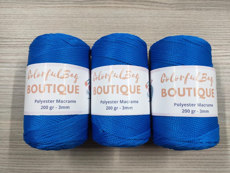 May include: Three spools of vibrant blue polyester macrame cord, each wrapped in a white paper label featuring the text Colorful Bag BOUTIQUE, Polyester Macrame, 200 gr - 3mm. The cord has a smooth, braided texture and a consistent bright blue color.