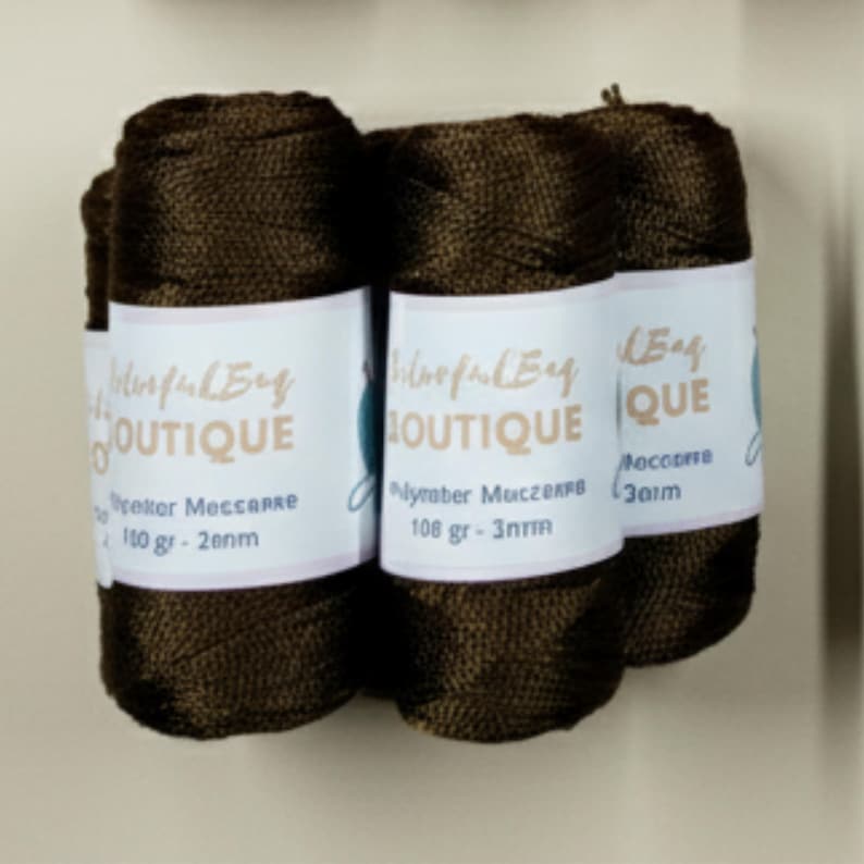May include: Three spools of dark brown macrame cord wrapped in a woven texture. Each spool features a white paper label with the text ColorfulBag BOUTIQUE, Polyester Macrame, 108 gr, and 3mm printed in black and tan ink on the front surface.