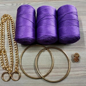 May include: Three spools of vibrant purple cord, a long gold-tone metal chain with two circular rings at the ends, two large gold-tone circular hoops, and a small gold-tone magnetic snap button fastener for crafting and bag making projects.