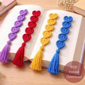 以下が含まれることがあります： 紫、赤、黄色、青色の、かぎ針編みで作られたハートのブックマーク。それぞれにタッセルが付いています。ブックマークは開いた本の中にあります。「PDF Instant Download」の文字も表示されています。