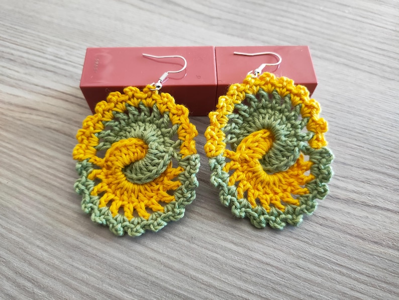 May include: A pair of crocheted earrings with a yellow and green swirl design.