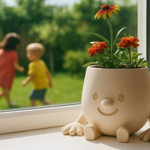 Könnte beinhalten: Ein skurriler, beigefarbener Keramik-Blumentopf in Form eines lächelnden Gesichts mit Armen und Beinen. Der Topf enthält leuchtend orange und gelbe Blumen mit grünem Laub. Im Hintergrund spielen zwei Kinder.