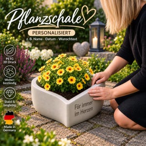 Könnte beinhalten: Eine herzförmige, hellgraue Pflanzschale aus PETG-3D-Druck mit der deutschen Aufschrift 'Für immer im Herzen' auf der Vorderseite. Die Schale enthält eine leuchtend gelbe Blumenpflanze und ist wetterbeständig sowie stabil und langlebig gefertigt.