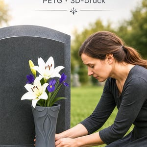 Może przedstawiać: Ciemnoszary wazon nagrobny wydrukowany w technologii 3D z materiału PETG, ozdobiony nowoczesnym wzorem krzyża. Wazon wypełniają białe lilie i fioletowe irysy. Tekst powyżej brzmi: Grabvase mit modernem Kreuz, PETG, 3D-Druck.