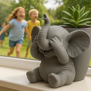 Puede incluir: Una maceta gris con forma de elefante con la trompa levantada y las manos cubriendo los ojos. La maceta contiene una planta suculenta verde. Niños jugando fuera de una ventana en el fondo.