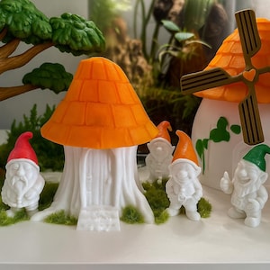 Puede incluir: Una escena de jardín caprichosa con gnomos blancos en miniatura con sombreros coloridos, un árbol y casas con forma de hongo. Los gnomos tienen sombreros azules, rojos y verdes. Las casas con forma de hongo tienen tejados naranjas.