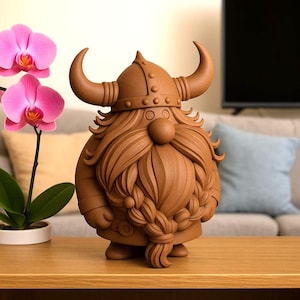 Könnte beinhalten: Eine braune Zwergfigur mit Wikingerhelm und Hörnern. Der Zwerg hat einen langen, geflochtenen Bart und steht auf einer Holzoberfläche. Im Hintergrund befinden sich rosa Orchideen.