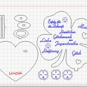 May include: Laser-cut design featuring a heart, clover, and other shapes. The heart has the name "Lucia" in red. The clover includes German text, such as "Erfolg für die Zukunft" and "Herzlichen Glückwunsch".