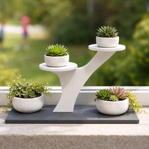 Puede incluir: Una taza de cerámica blanca con un asa negra y el texto "But First, Coffee" en un estilo manuscrito. La taza está sobre una superficie blanca. La taza mide 10 cm de alto.