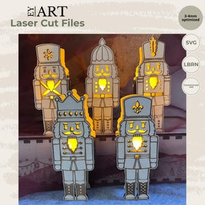 May include: Five laser-cut wooden nutcracker figures with light-colored surfaces and glowing yellow cutouts. The figures feature various hat styles, including a crown and tall caps. Text on the image includes EY ART, Laser Cut Files, 3-4mm optimized, SVG, LBRN, and Commercial use.