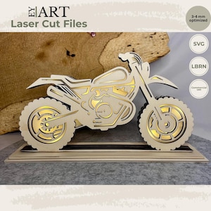 Peut inclure: Un modèle de moto en bois découpé au laser avec des panneaux superposés, une finition claire et des accents dorés. Le design comprend des roues détaillées, un cadre et une selle, le tout monté sur une base rectangulaire. Texte EY ART Laser Cut Files.