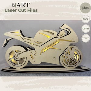 Peut inclure: Un modèle de moto en bois découpé au laser présentant une conception en couches avec des panneaux en bois clair et des accents dorés. La structure est montée sur une base ovale et inclut les textes EY ART, Laser Cut Files, 3-4 mm optimized, SVG, LBRN et Commercial use.