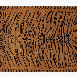 May include: A rectangular rug with a golden-brown background and black, vertical stripe patterns. The rug has a black border with decorative elements. The design resembles tiger stripes, adding a bold and stylish touch to any room.