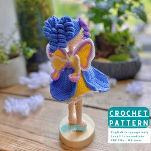 May include: Crochet pattern for a fairy doll with blue hair, yellow and purple wings, and a blue and yellow dress. The pattern is for an intermediate level crocheter and is written in English. The pattern is available as a PDF file.
