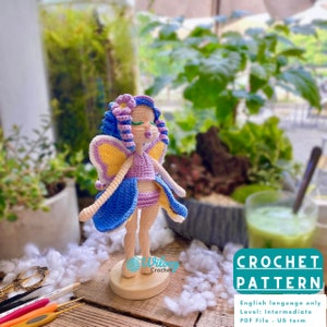 May include: Crochet pattern for a purple and blue fairy doll with yellow wings. The pattern is written in English and is for an intermediate skill level. The pattern is available as a PDF file in US terms.