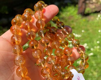 May include: Three stacked bracelets made of golden citrine beads. Each bracelet has a white tag with the word "Citrine" written in pink.