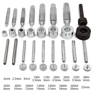 May include: A set of 14 metal leather hole punch tools with different sizes, ranging from 2mm to 25mm. The tools are silver and have a textured surface. The set includes a punch tool, a hammer, and a set of dies.