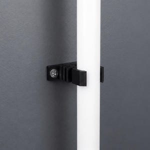 K&ouml;nnte beinhalten: Ein schwarzer Kunststoff-Wandclip mit geripptem Design und einer einzelnen silberfarbenen Schraube, der eine glatte, vertikale wei&szlig;e zylindrische Stange fest gegen eine dunkelgraue Oberfl&auml;che h&auml;lt.