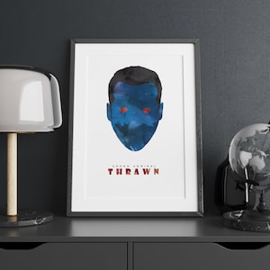 May include: A framed print of a blue and red watercolor portrait of Grand Admiral Thrawn. The portrait is set against a white background with the text "Grand Admiral Thrawn" printed below the portrait.